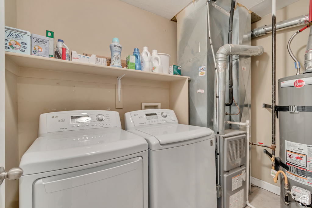 Washroom with independent washer and dryer, laundry area, strapped water heater, and heating unit