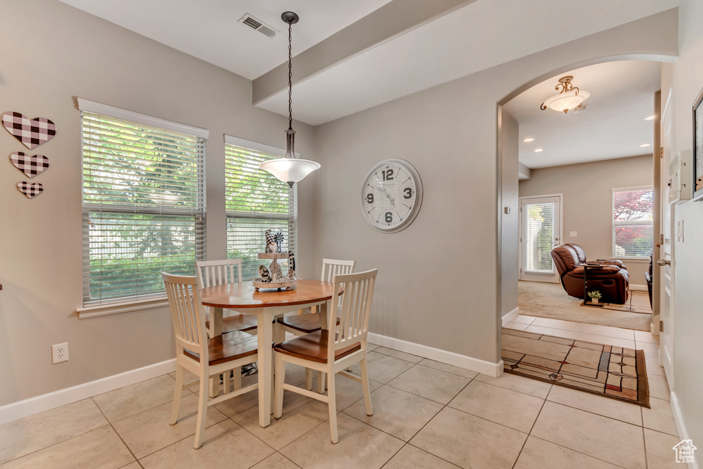 Dining room featuring arched walkways, baseboards, visible vents, and light tile patterned floors