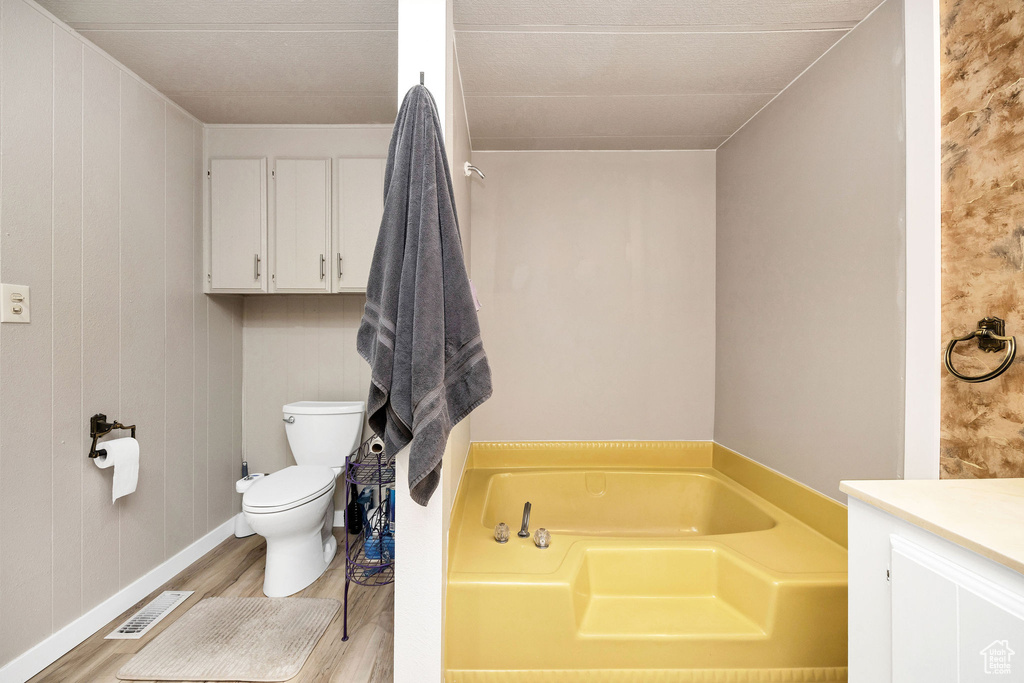 Full bath with a bath, visible vents, wood finished floors, vanity, and toilet
