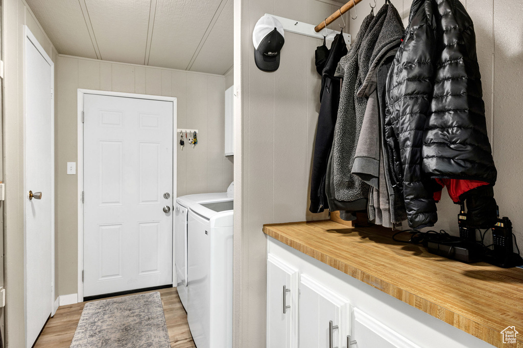 Clothes washing area featuring cabinet space, separate washer and dryer, and light wood finished floors