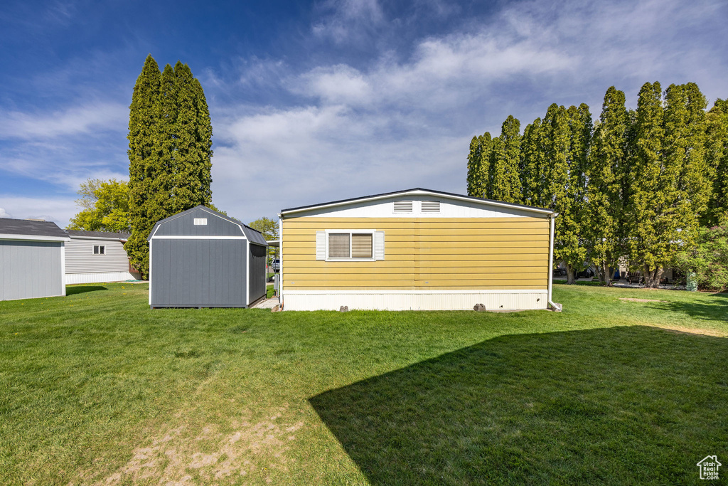 Back of house featuring a storage shed, an outdoor structure, and a lawn