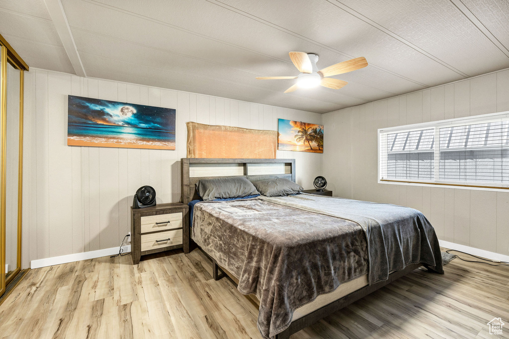 Bedroom featuring wooden walls, baseboards, ceiling fan, and wood finished floors