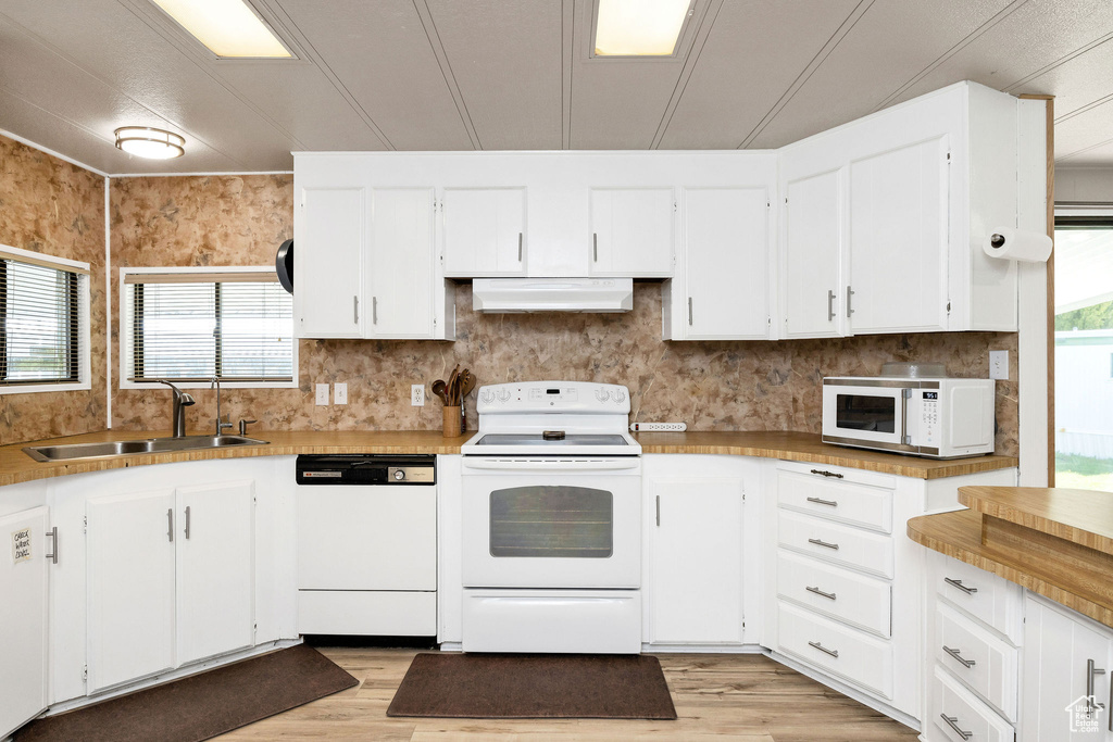 Kitchen featuring white appliances, extractor fan, a sink, and light wood-type flooring