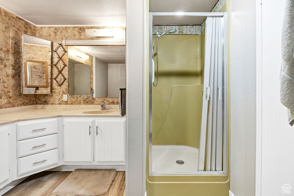 Bathroom featuring vanity, a shower stall, and wood finished floors