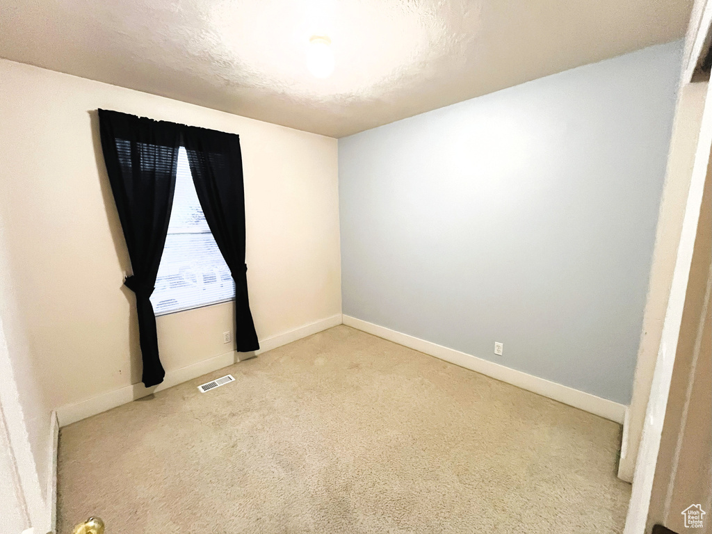 Spare room with baseboards, light colored carpet, and visible vents