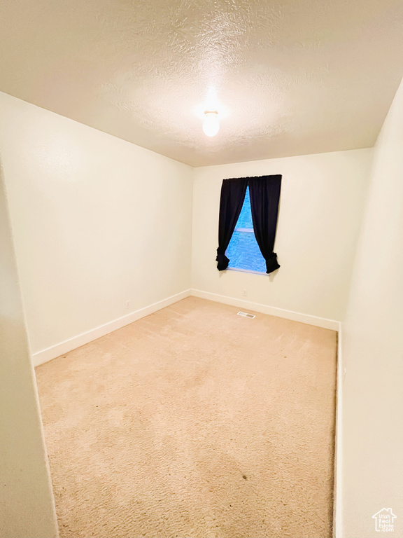Unfurnished room with a textured ceiling, visible vents, light carpet, and baseboards