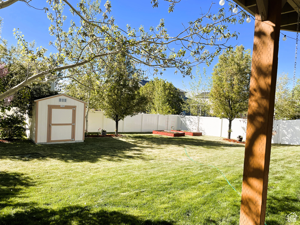 View of yard featuring a fenced backyard, a storage unit, and an outbuilding