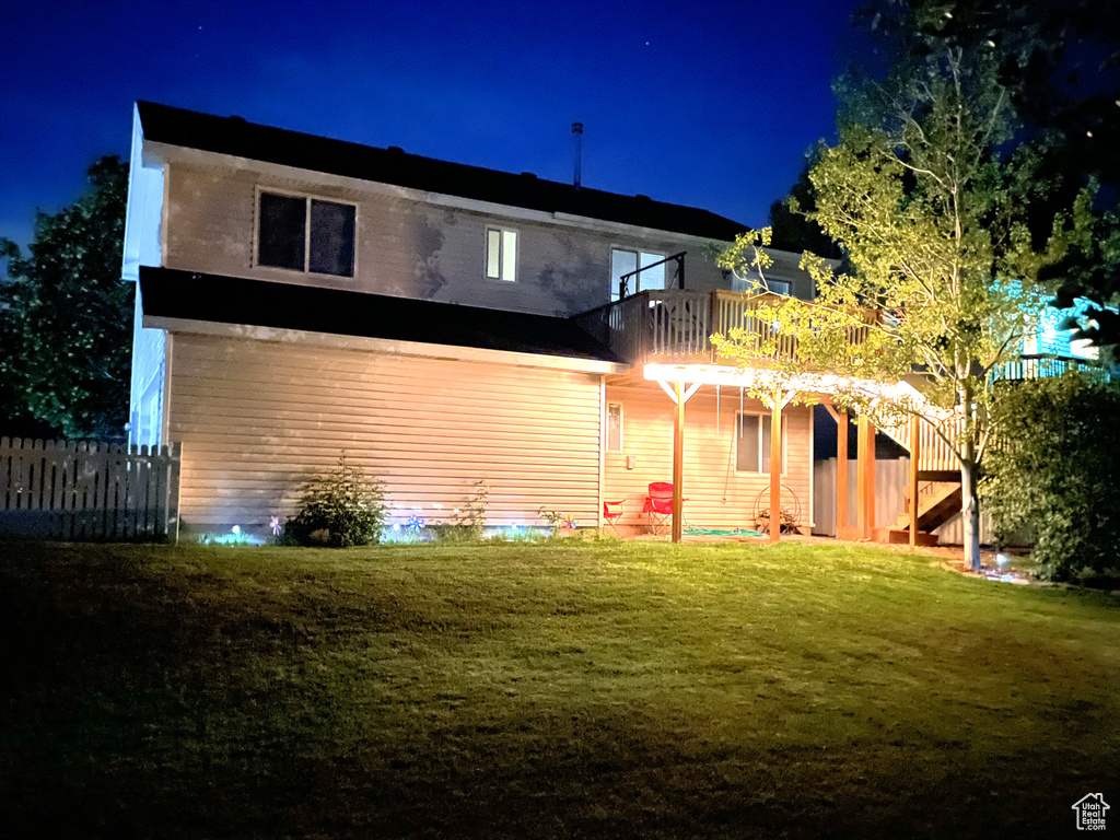 Back of house at night with a deck and stairs