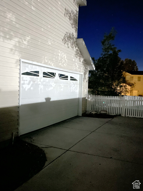 Garage at twilight featuring concrete driveway