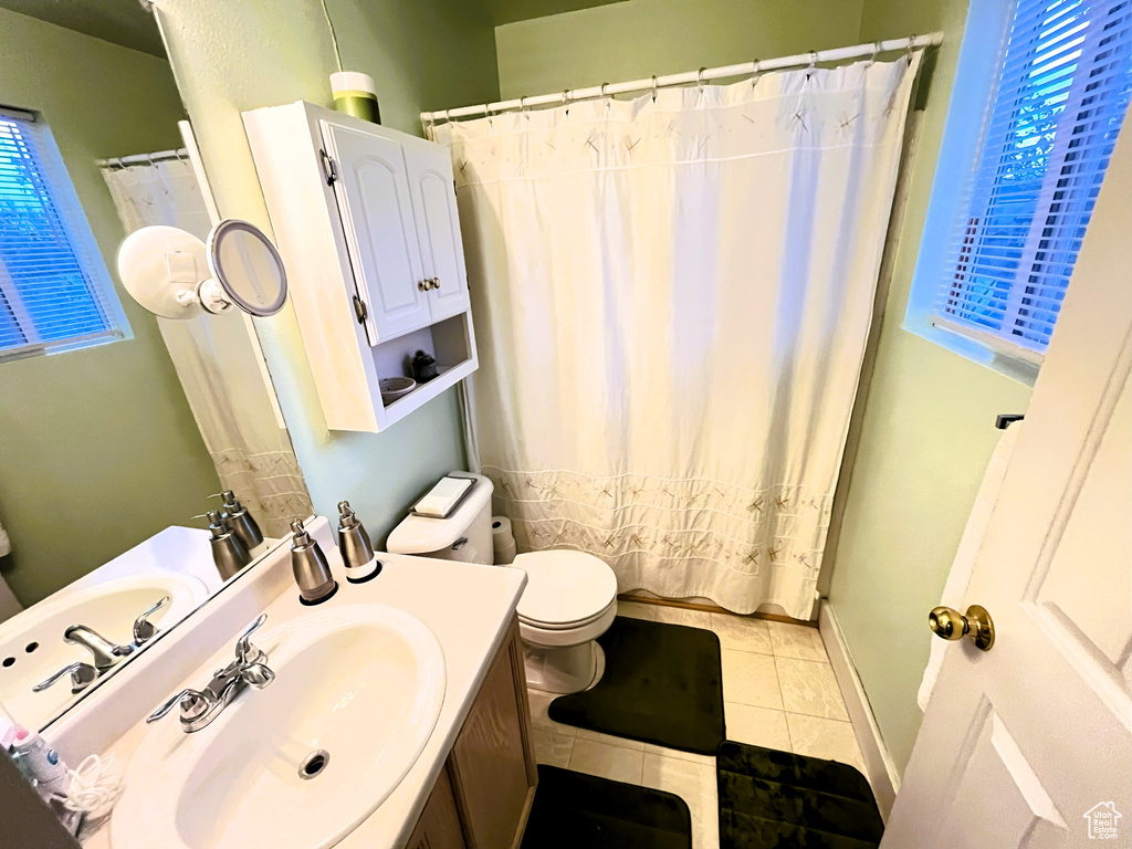 Full bathroom with toilet, a healthy amount of sunlight, tile patterned flooring, and vanity