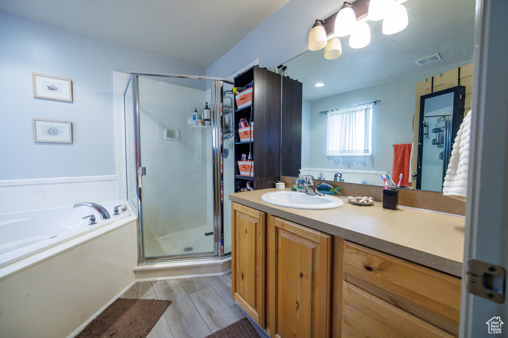 Bathroom with vanity, wood finished floors, visible vents, a garden tub, and a stall shower