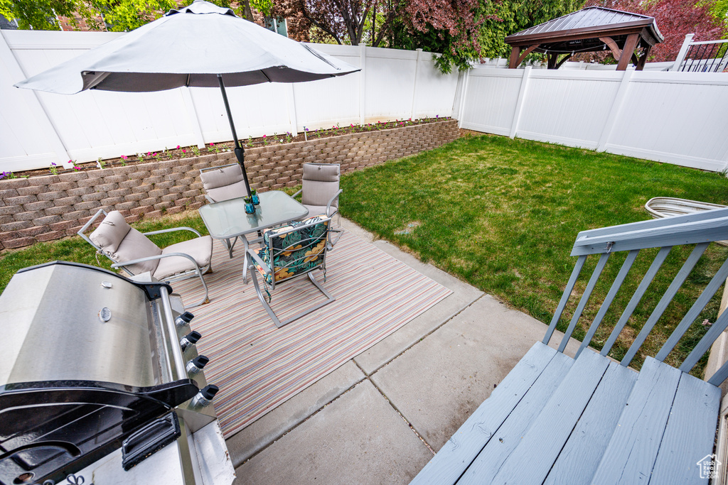 Wooden deck featuring a gazebo, a fenced backyard, a lawn, and area for grilling