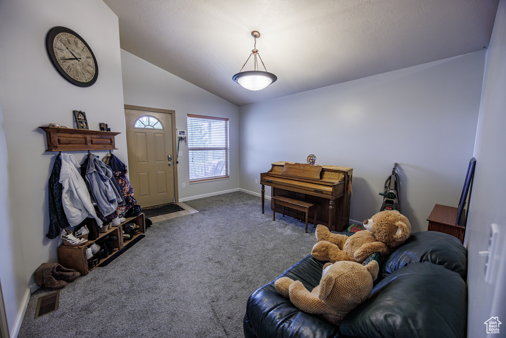 Carpeted living area featuring baseboards, vaulted ceiling, and visible vents