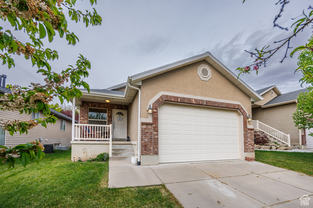 Ranch-style home featuring a porch, a garage, brick siding, a front lawn, and concrete driveway