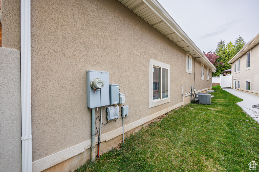 View of property exterior featuring a yard, fence, central AC unit, and stucco siding