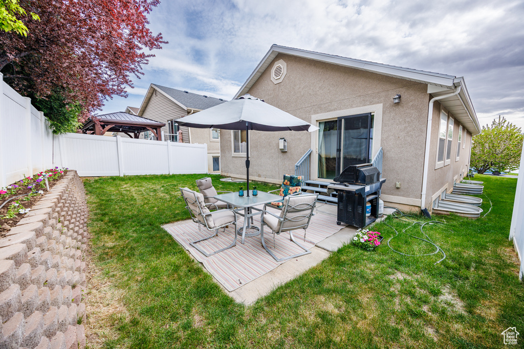 Rear view of house with a gazebo, a fenced backyard, a lawn, and stucco siding