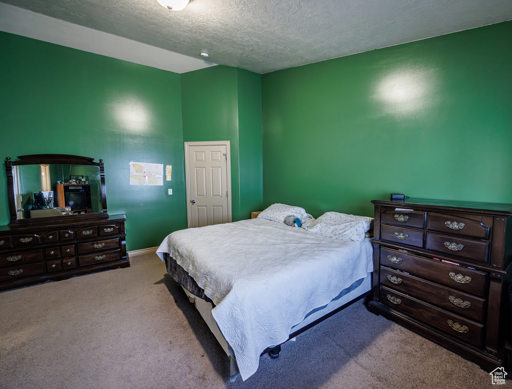 Bedroom featuring a textured ceiling, baseboards, and carpet
