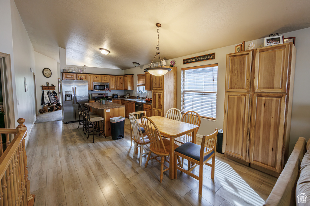 Dining room with light wood-style floors and vaulted ceiling