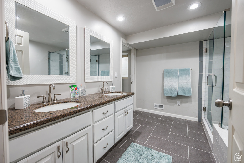 Bathroom with a sink, a stall shower, and visible vents