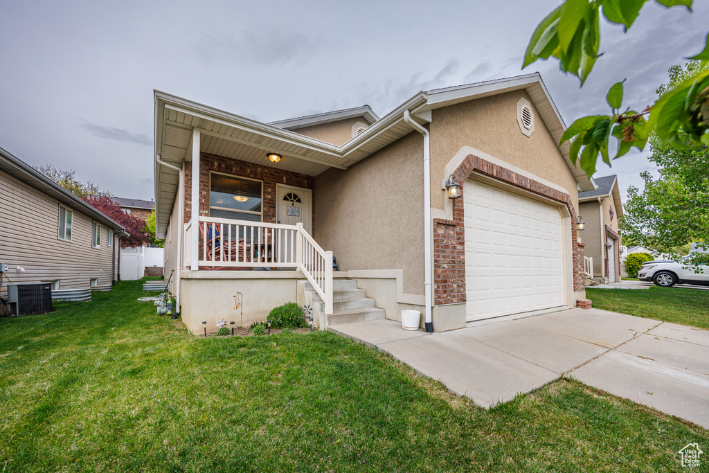 View of front facade with a garage, a front yard, stucco siding, concrete driveway, and central air condition unit