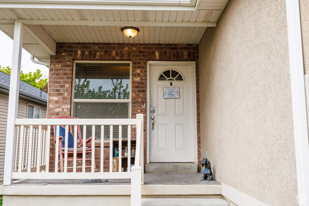 View of exterior entry featuring stucco siding and covered porch