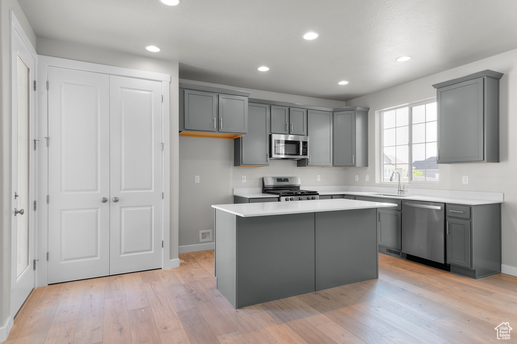 Kitchen featuring stainless steel appliances, gray cabinets, a sink, a kitchen island, and recessed lighting