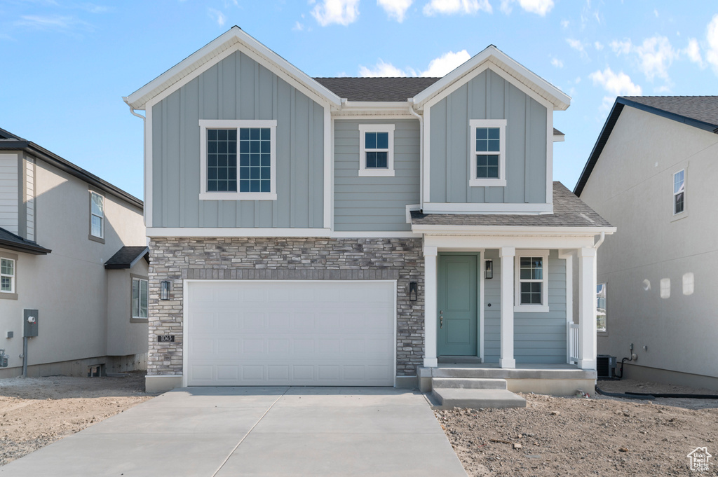 View of front of property with board and batten siding, concrete driveway, and stone siding