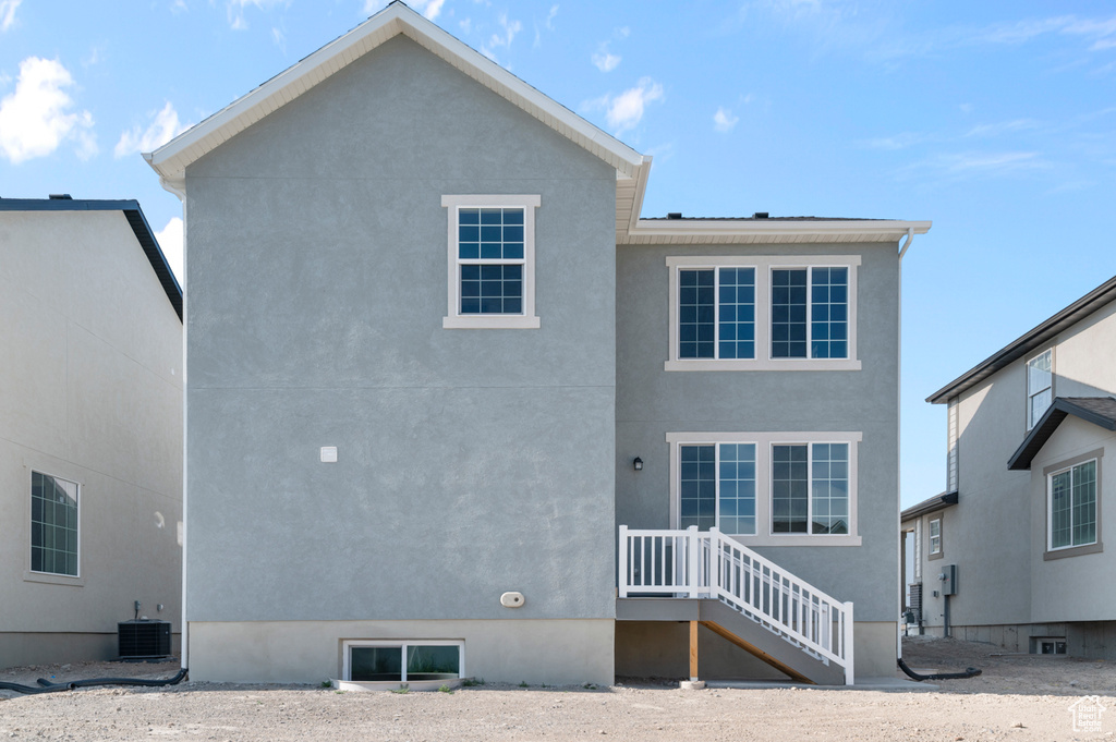 Rear view of property featuring central air condition unit and stucco siding