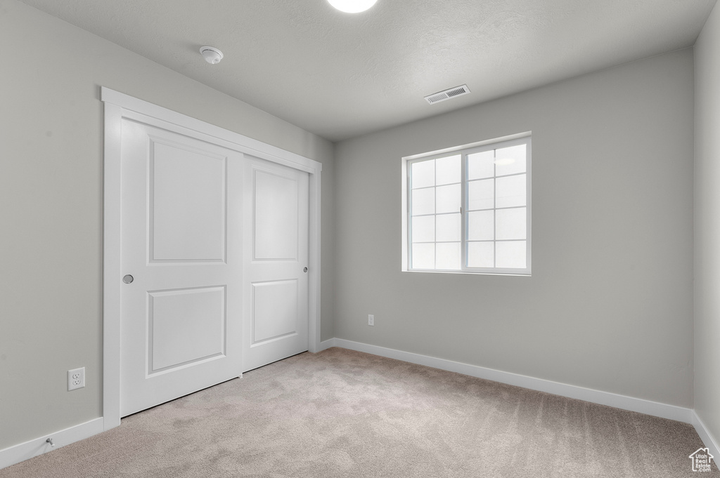 Unfurnished bedroom with light colored carpet, baseboards, and a closet
