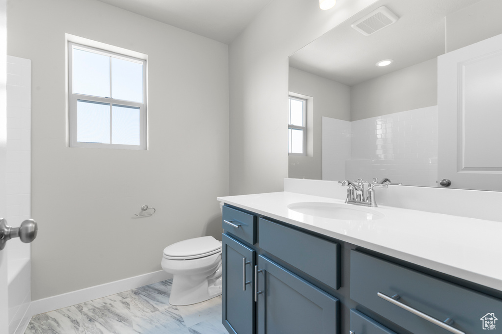 Full bathroom featuring vanity, toilet, marble look tile flooring, baseboards, and bathtub / shower combination