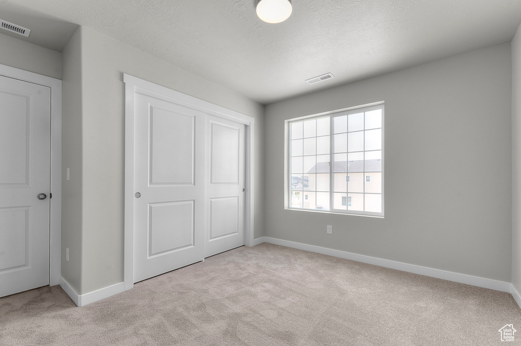 Unfurnished bedroom featuring carpet flooring, baseboards, a closet, and a textured ceiling