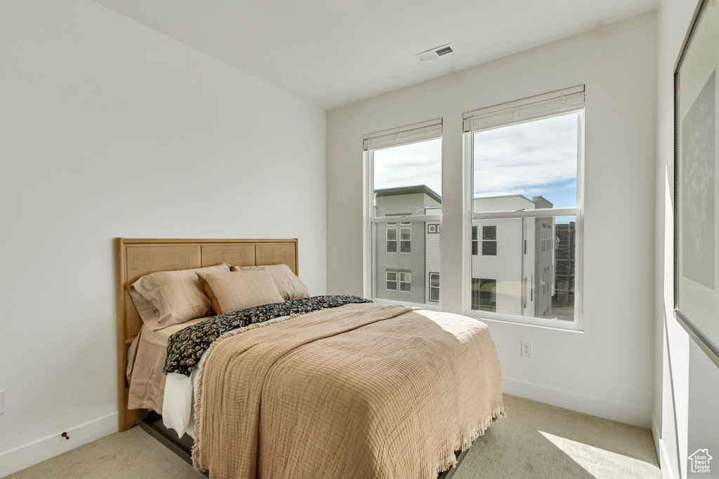 Bedroom with light colored carpet, baseboards, and visible vents