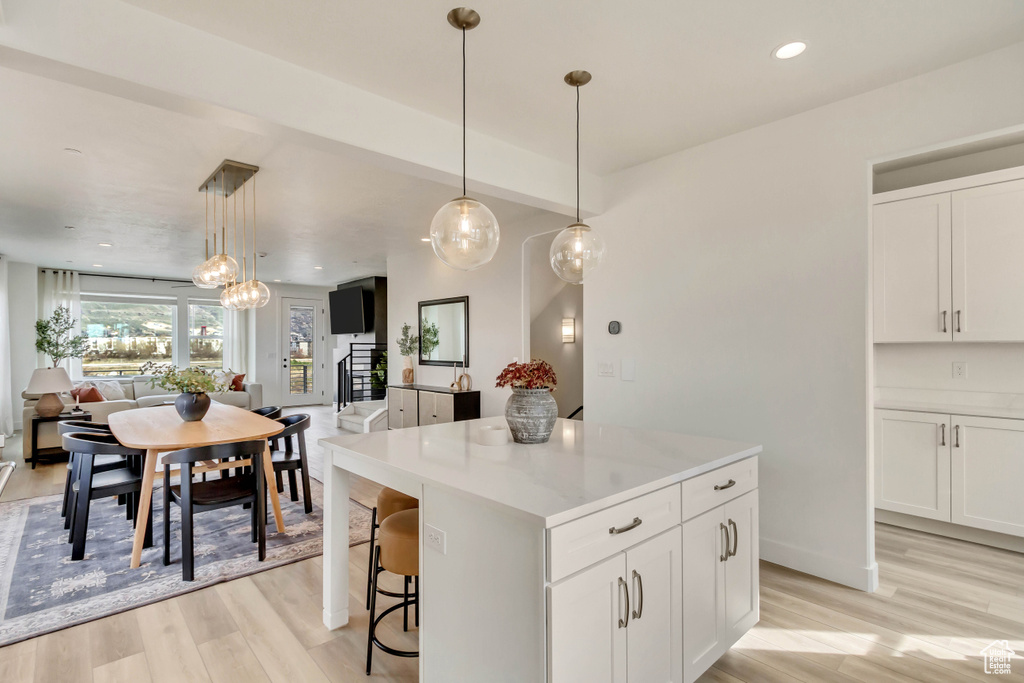 Kitchen with a center island, open floor plan, light wood-style flooring, and white cabinets