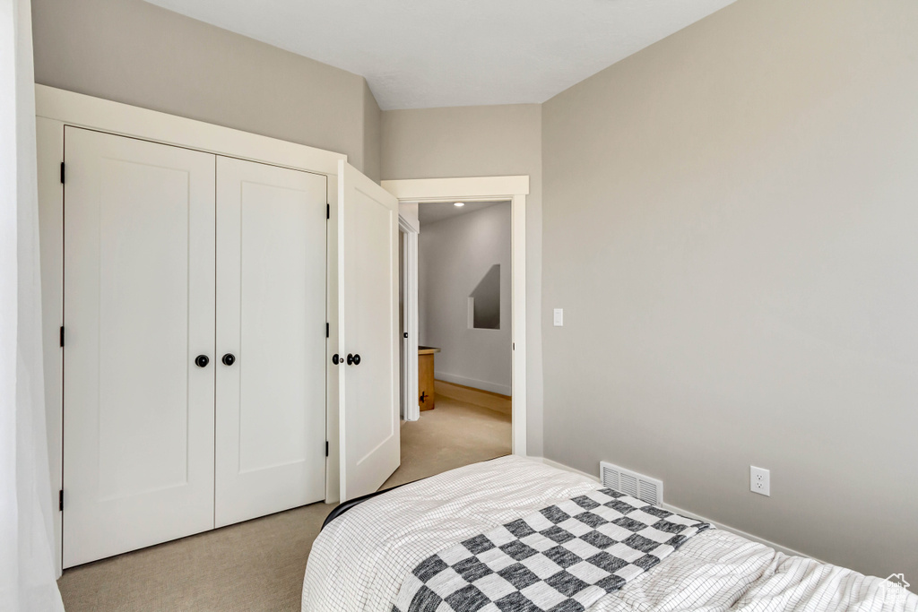 Bedroom featuring visible vents, a closet, and light carpet