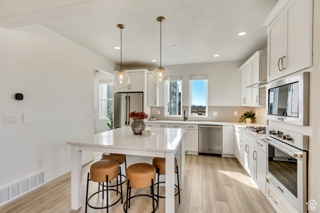Kitchen featuring visible vents, light wood-style flooring, white cabinetry, and stainless steel appliances