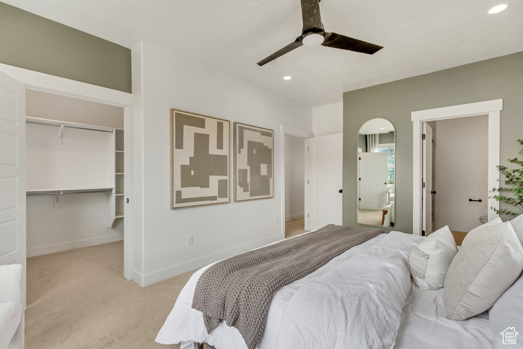 Bedroom with recessed lighting, ceiling fan, light colored carpet, and a walk in closet