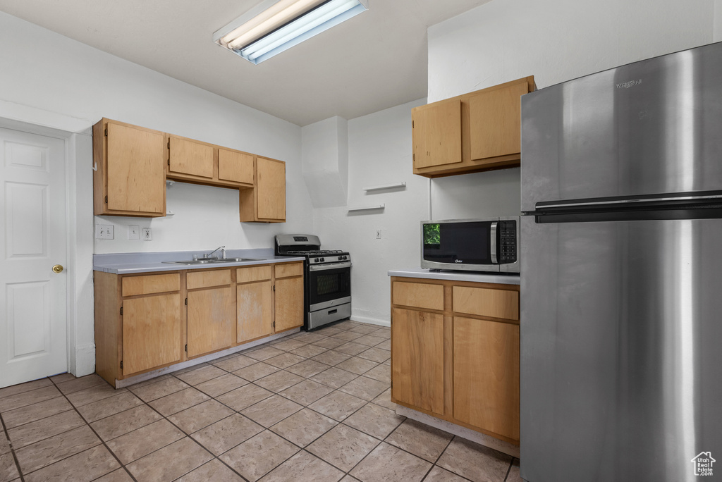 Kitchen with light countertops, a sink, appliances with stainless steel finishes, and light tile patterned floors