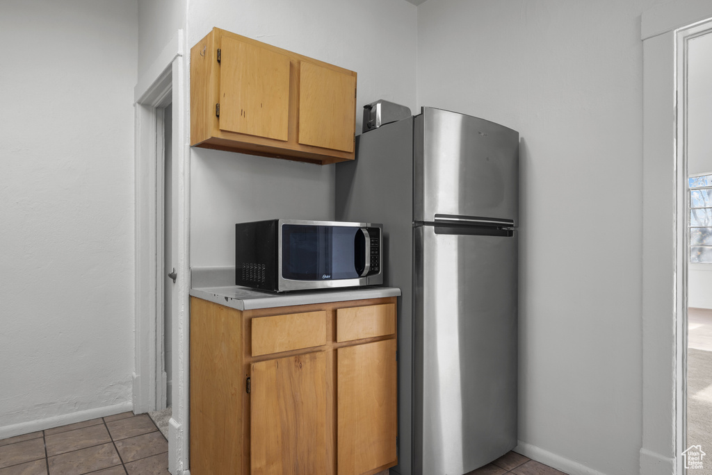Kitchen with baseboards, light countertops, light tile patterned floors, and stainless steel appliances