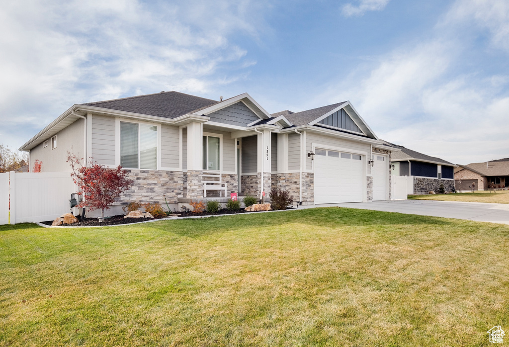 Craftsman inspired home with driveway, a garage, fence, a front lawn, and stone siding