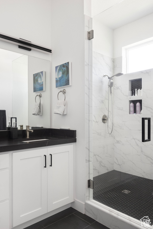 Full bath with a marble finish shower, vanity, and tile patterned floors