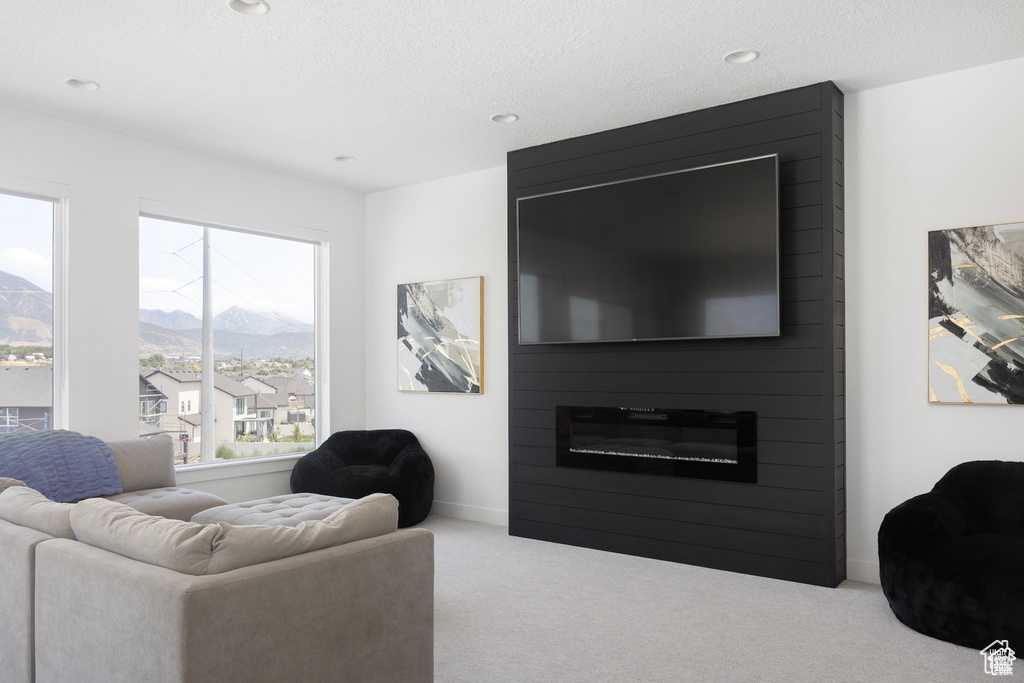 Carpeted living area featuring baseboards, recessed lighting, a mountain view, and a fireplace