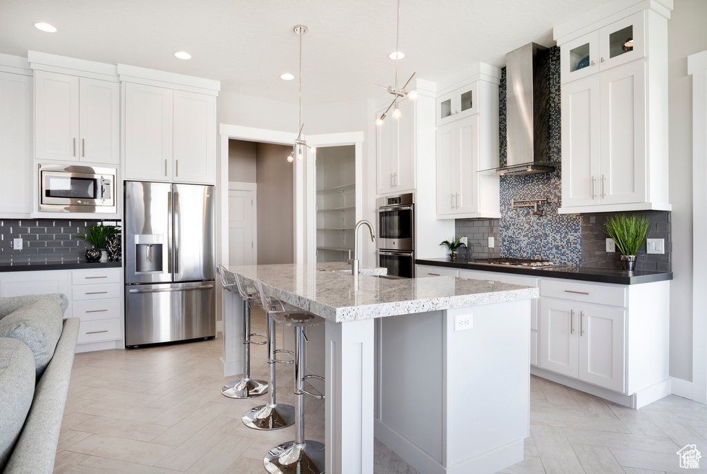 Kitchen featuring decorative backsplash, glass insert cabinets, stainless steel appliances, recessed lighting, and wall chimney exhaust hood