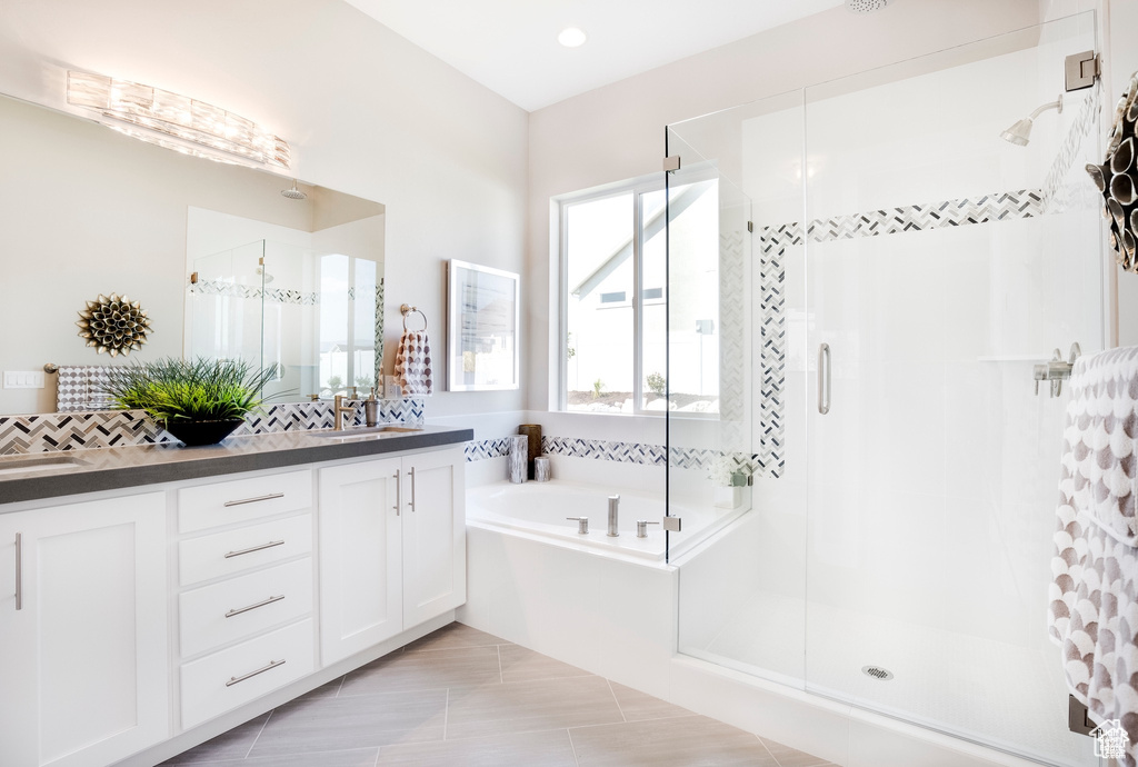 Bathroom featuring a garden tub, a sink, a stall shower, and double vanity