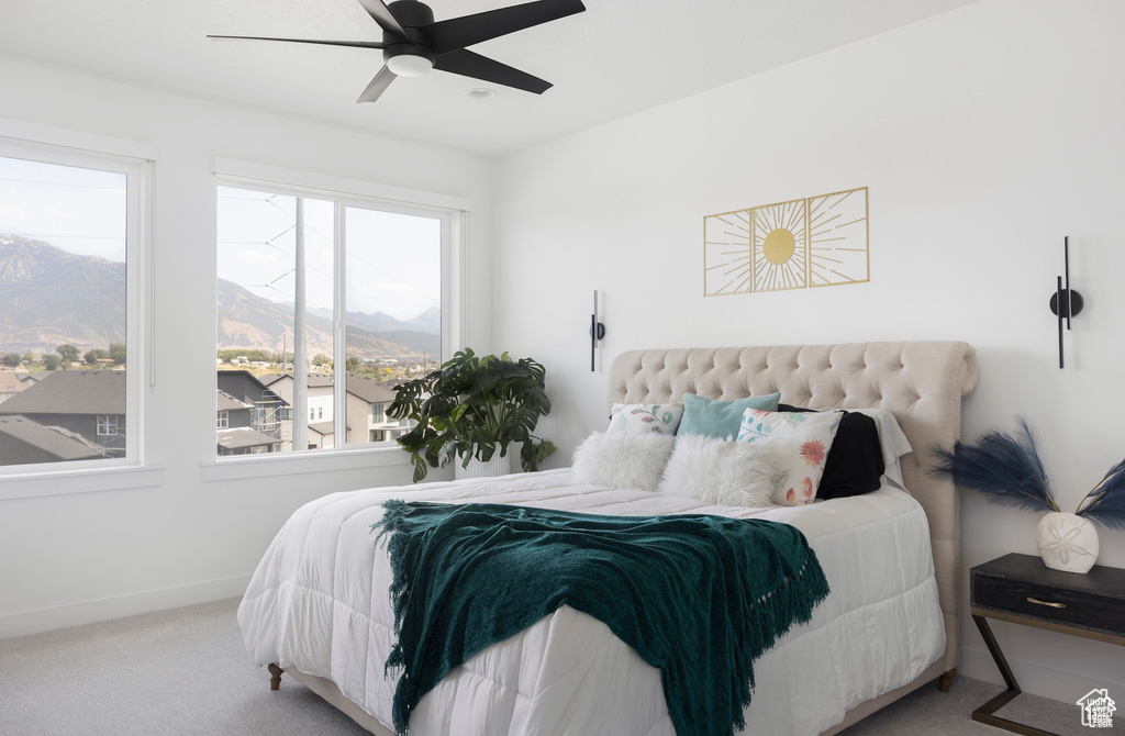 Bedroom featuring baseboards, a ceiling fan, carpet flooring, and a mountain view