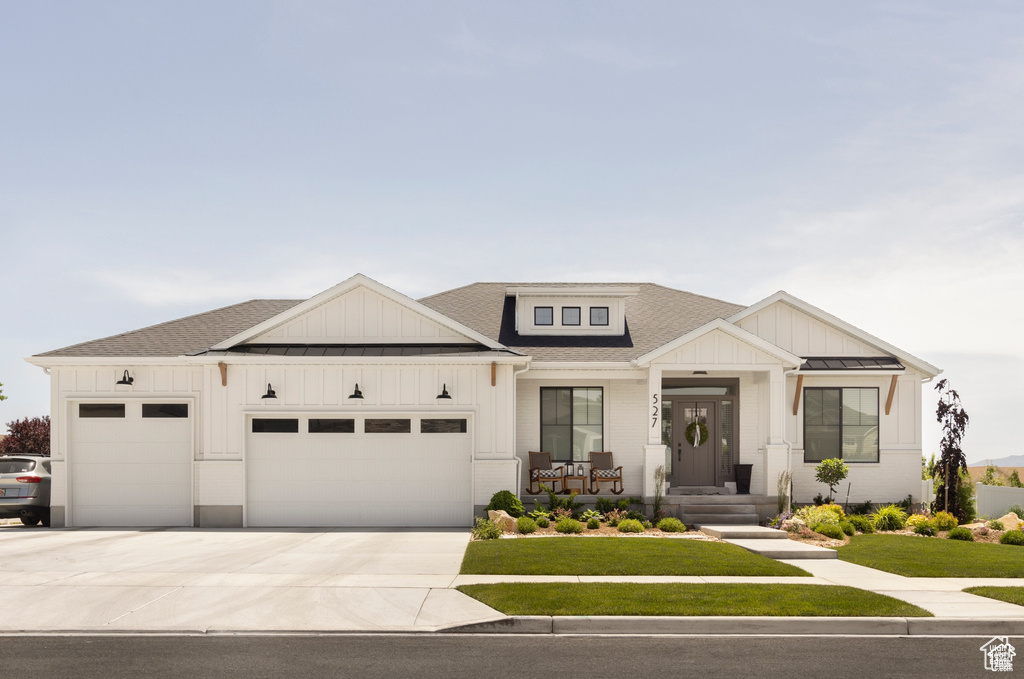 View of front facade featuring a garage, board and batten siding, a shingled roof, and driveway
