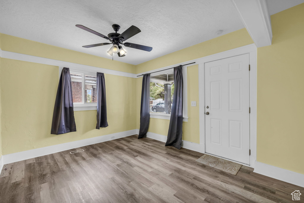 Empty room with baseboards, wood finished floors, a wealth of natural light, and visible vents
