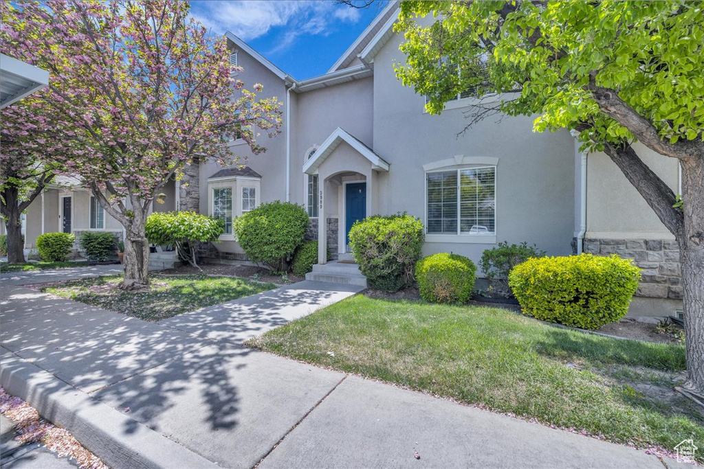 View of front of home with a front yard, stone siding, and stucco siding