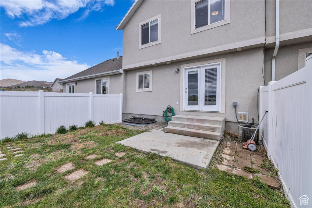 Rear view of house featuring central air condition unit, a fenced backyard, entry steps, and stucco siding