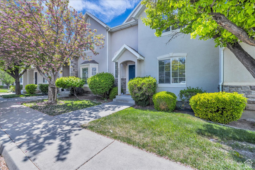 View of front of home featuring stucco siding, a front lawn, and stone siding