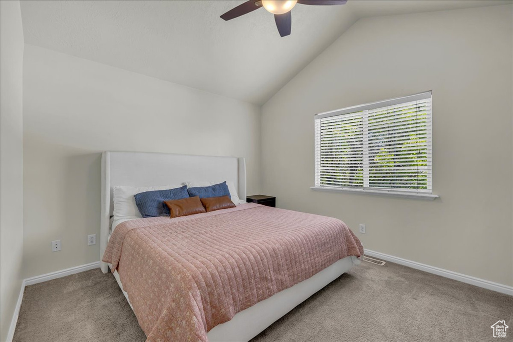 Carpeted bedroom featuring a ceiling fan, baseboards, visible vents, and lofted ceiling